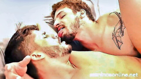 Two bearded muscular men passionately kissing with tattoos visible