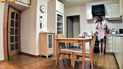 Japanese housewife in pink apron and skirt standing at kitchen counter from behind
