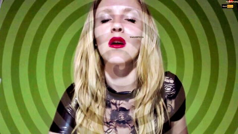 Seductive blonde in sheer black lace top with hypnotic green spiral background for femdom JOI dirty talk