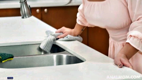 Misty Meaner in pink dress bending over sink, curvy MILF tease