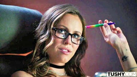 Stella Barey as campus bad girl in glasses, choker, and tattoos holds rainbow pen