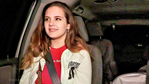 Smiling teen pornstar in green Pornstar hoodie sitting in car passenger seat at night