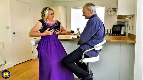 Mature blonde squeezes huge tits through black lace bra for older man at kitchen counter