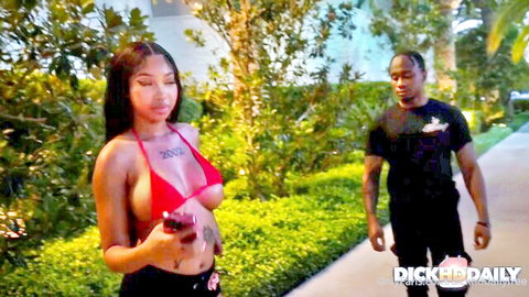 Wicca LaVey in skimpy red bikini outdoors with muscular man, teasing vibe