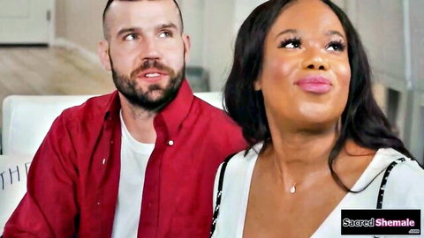 Ebony shemale puckers plump lips seductively at bearded boyfriend on couch