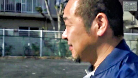 Profile view of mature Asian man in blue jacket smiling outdoors