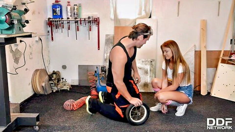 Redhead teen babe in knee socks and tiny denim shorts squats sensually with mechanic fixing scooter wheel