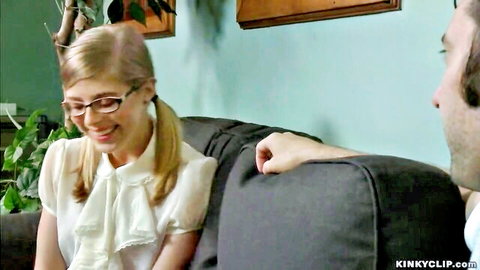 Blonde schoolgirl with glasses and pigtails smiles submissively on couch with man