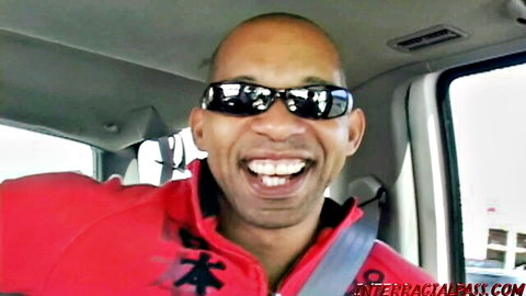 Bald black man grinning in sunglasses and red hoodie inside car on interracialabuse