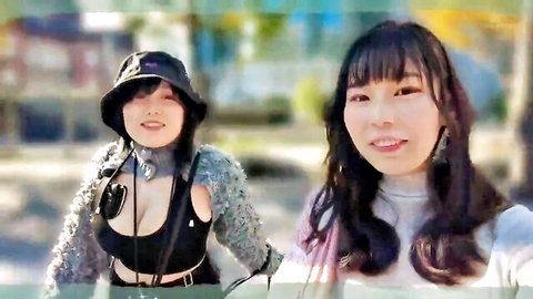 Two smiling Asian women outdoors, one in cleavage-baring top and hat, JAV style