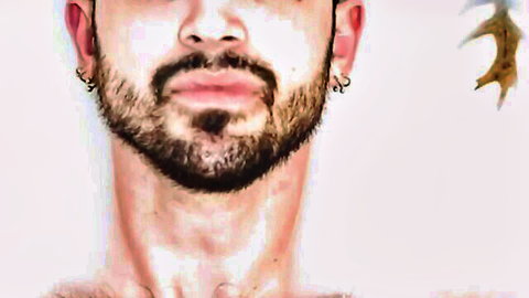 Close-up portrait of handsome bearded man with hoop earrings and bare neck