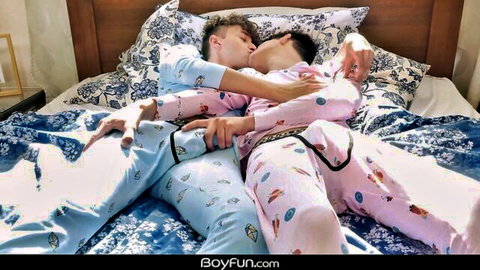Two twinks cuddling and kissing in matching pajamas on a lazy morning