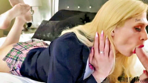 Blonde trans woman in schoolgirl outfit sucking big cock with red lips on bed