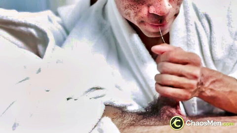 Two men passionately kissing in white bathrobes, exposing pierced cock
