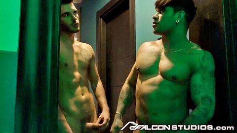 Two muscular tattooed men posing intimately in steamy green-lit spa