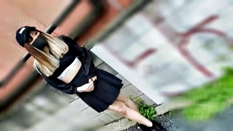 Blonde JAV model in sexy crop top and mini skirt posing against graffiti wall