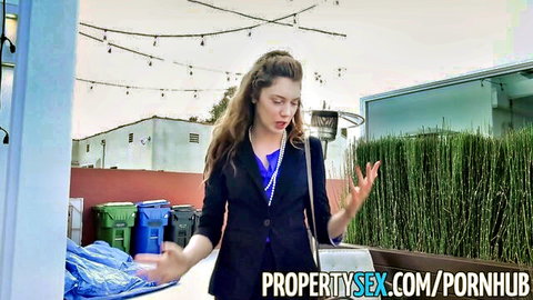 Stunning brunette real estate agent in black blazer gesturing outdoors