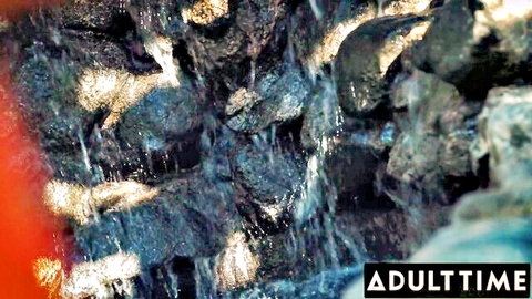 Blurry dark rocks and flowing water in cave-like scene with AdultTime watermark