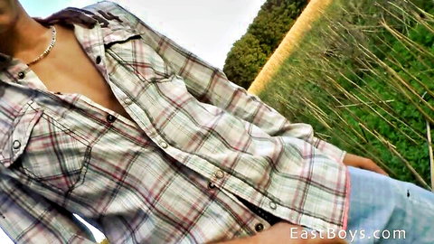 Slim Asian guy in open plaid shirt teases outdoors in public park - East Boys solo