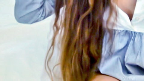 Monik C posing in unbuttoned blue blouse, long wavy brown hair, sexy MetArt intro