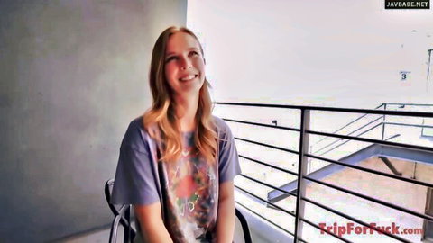 Smiling blonde wife in casual t-shirt on balcony