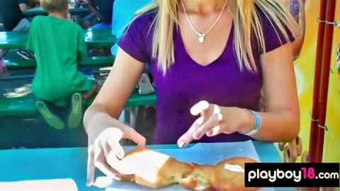 Blonde babe in purple V-neck top biting thick braided bread outdoors