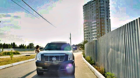 Skinny brunette in short white dress teasing by Cadillac Escalade outdoors