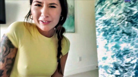 Charlotte Mae smiling in tight yellow top, Asian beauty with tattoos and braids