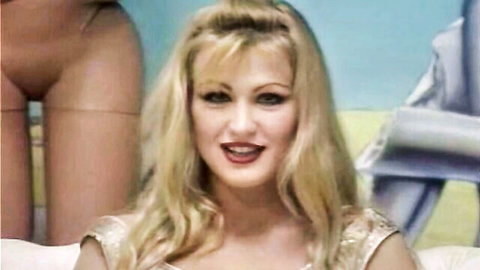Eva Henger in gold sparkly top with deep cleavage, blonde bombshell posing seductively, 1999 Italian adult film