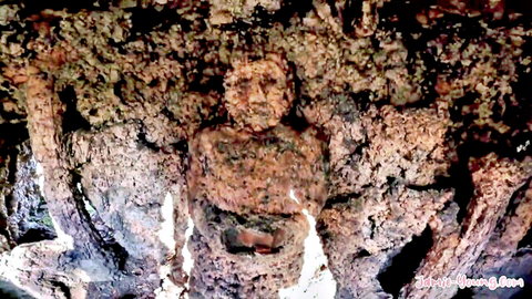 Mysterious carved stone face in rocky cave, ancient statue emerging from rock