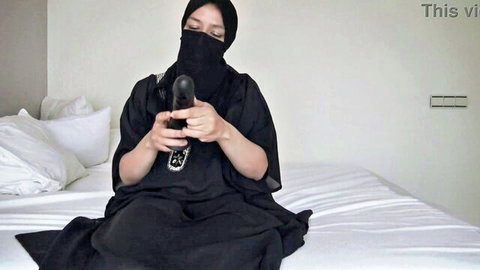 Veiled Arab niqab woman teases fat black dildo near mouth on bed