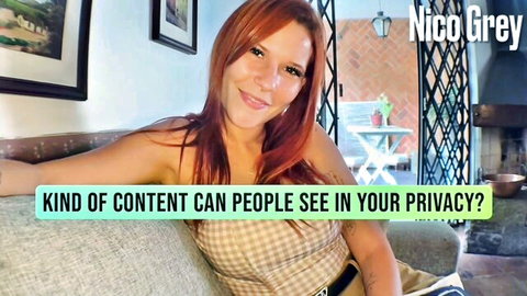 Sexy redhead NicoGrey smiles teasingly in cropped top on couch showing cleavage