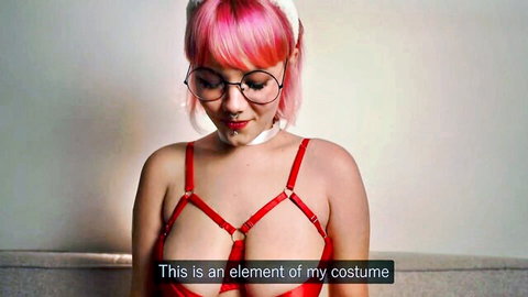 Pink-haired Asian woman in red harness lingerie and glasses, costume tease