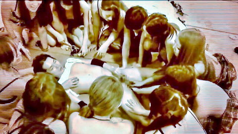 Group of blonde women surrounding and pleasuring nude man in erotic scene