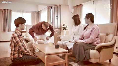 Clothed Japanese man bending over table while others sit in cozy living room