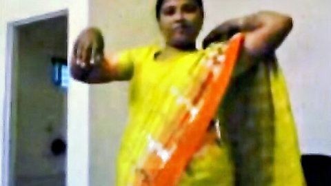 Mature Indian housewife in yellow sari lifts arms teasing curves solo