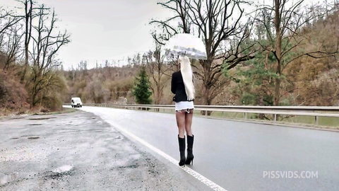 Blonde in tiny white shorts and boots struts seductively on wet forest road with umbrella