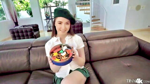 Hazel Moore in sexy schoolgirl outfit holding candy bowl, smiling seductively