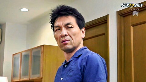 Serious Japanese man in blue shirt standing in kitchen looking intense