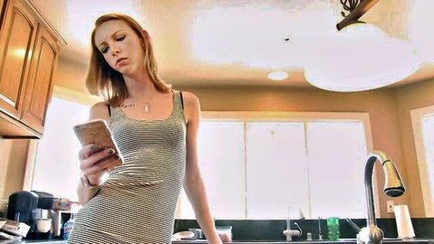 Redhead in tight striped dress posing seductively in kitchen