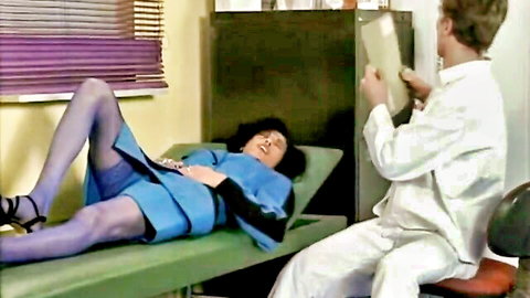 Nadine Perrier as sexy nurse in blue uniform, legs spread on exam table with doctor