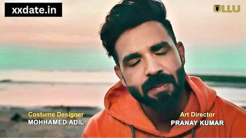 Bearded Indian man in orange hoodie gazing at sea, Jija Saali adult scene promo