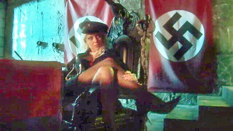 Blonde policewoman in leather jacket fishnets and high heels sits seductively on throne amid Nazi flags