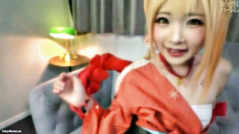 Blonde Asian cosplay babe in red miko dress smiling with deep cleavage on couch