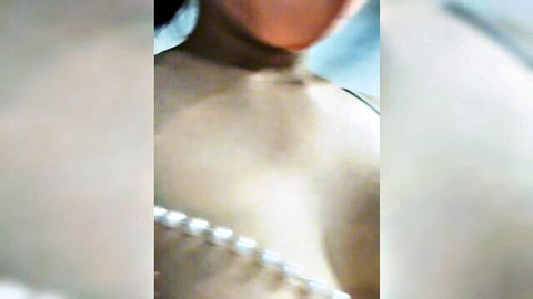 Blurry closeup of sexy Asian babe's neck and pearl necklace teasing deep cleavage.