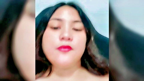 Closeup of seductive Asian webcam girl with red lips and closed eyes teasing in amateur selfie