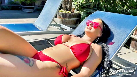 Curvy brunette with huge tits in skimpy red bikini lounging poolside teasing