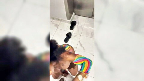 Curvy Black woman squatting exposed in elevator, rainbow armband, post-sex vibe