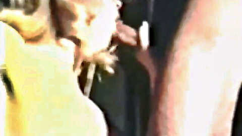Blonde woman in yellow top performing oral sex in classic hardcore scene