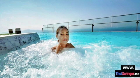 Hot smiling Asian babe relaxing topless in bubbly outdoor jacuzzi